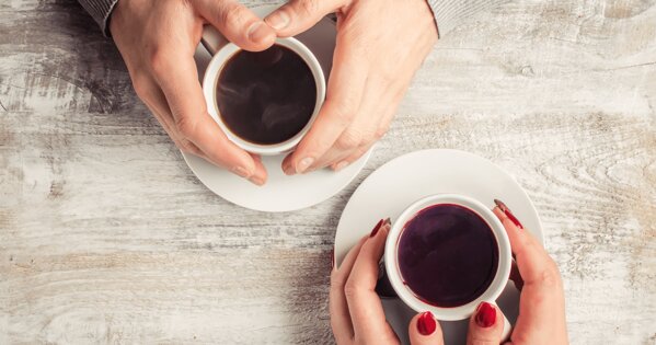 Zwei Hände mit jeweils einer Tasse Kaffee in der Hand
